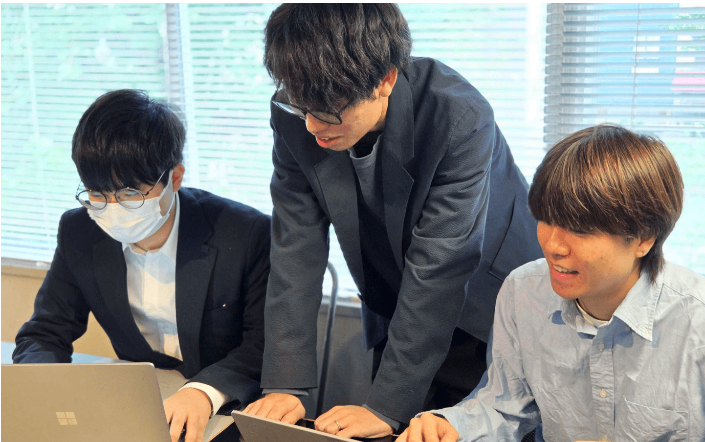 インターン生と社員がノートパソコンを覗き込んで話している様子