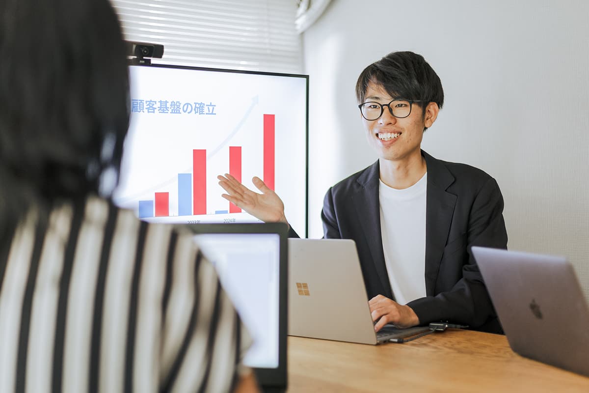 経営数値のグラフを示しながら説明する担当者